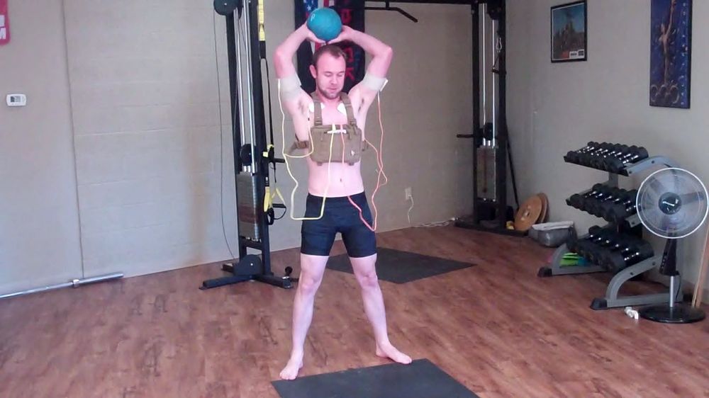 athlete doing medicine ball slams with electrode pads on arms increasing muscle activation with the direct current Phoenix Waveform
