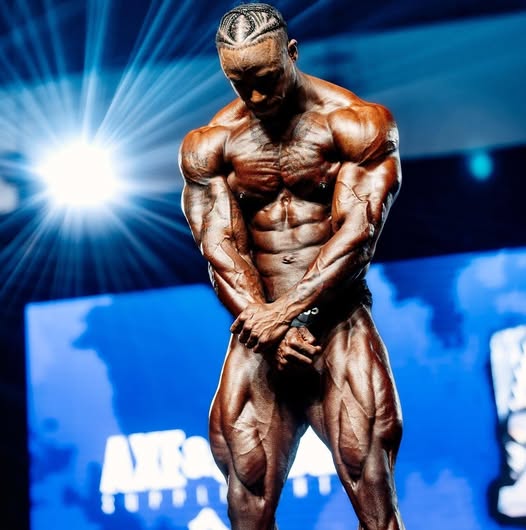 Bodybuilder on stage showing peak muscular development, representing advanced neuromuscular activation and performance enhancement with Phoenix Waveform