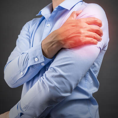 person holding their shoulder in pain, illustrating shoulder injury and rehabilitation with the Phoenix Waveform